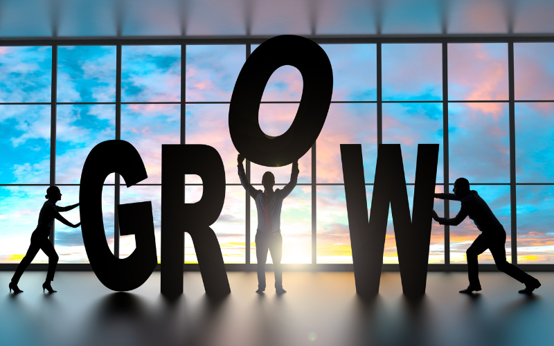 People holding or standing next to the letters G R and W in GROW